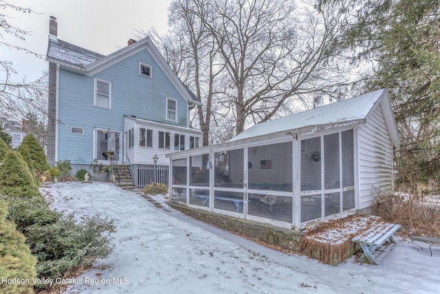 snow covered property featuring a sunroom