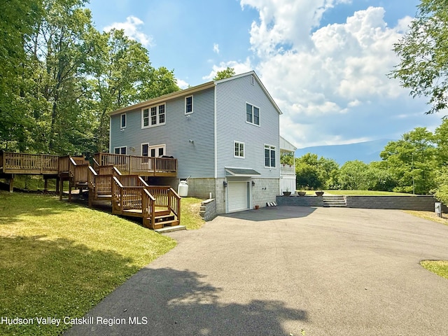 208 Paul Saxe Rd, Catskill, NY 12414 - back of house with stairs, asphalt driveway, a wooden deck, a lawn, and a garage