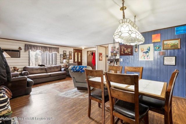 dining area featuring wooden walls and wood-type flooring