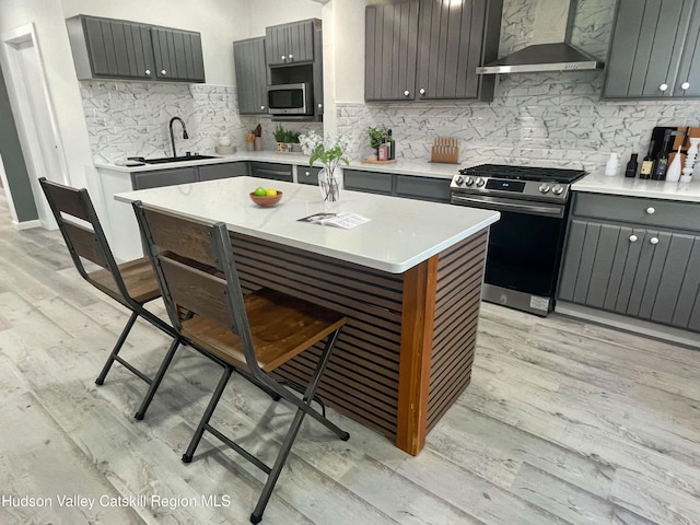 4947 Rte 32, Catskill, NY 12414 - kitchen featuring stainless steel appliances, wall chimney range hood, light wood-style floors, a breakfast bar, and a sink