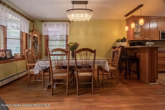 dining area with dark hardwood / wood-style floors, a baseboard radiator, and an inviting chandelier