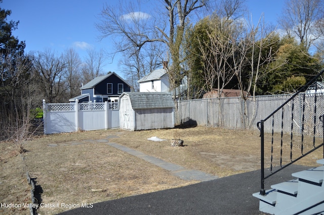 view of yard with an outbuilding, a fenced backyard, and a shed