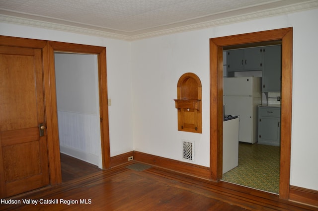 empty room featuring visible vents, a textured ceiling, wood finished floors, and crown molding