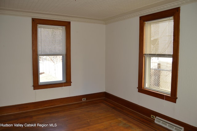 spare room featuring visible vents, crown molding, and wood finished floors