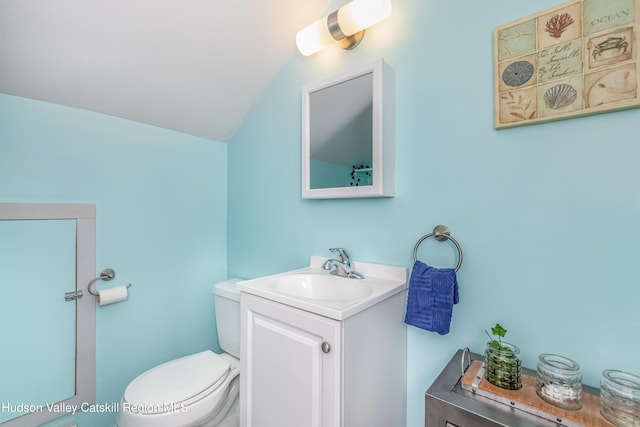 bathroom with toilet, lofted ceiling, and vanity