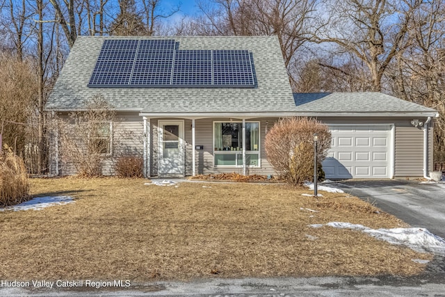 view of front of home featuring a garage, roof mounted solar panels, a shingled roof, and aphalt driveway