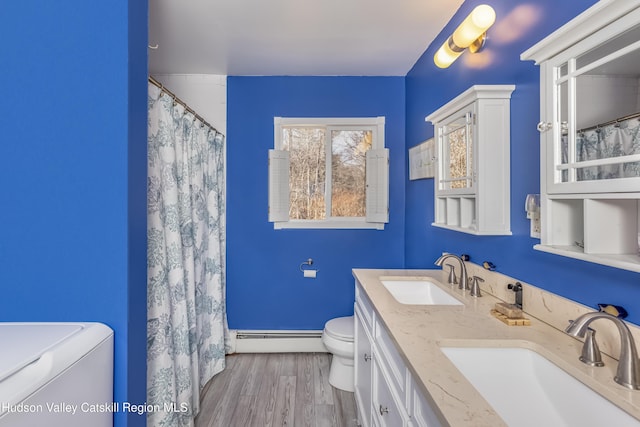 full bath with a baseboard heating unit, a sink, toilet, and wood finished floors