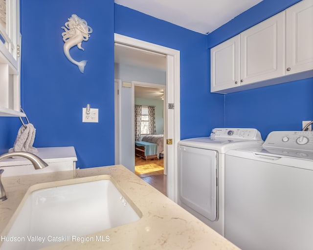 clothes washing area with a sink, cabinet space, and washer and dryer