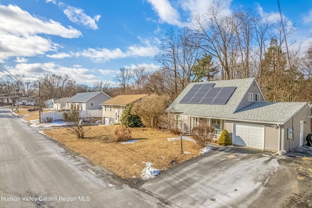 single story home featuring aphalt driveway, roof with shingles, solar panels, an attached garage, and a residential view