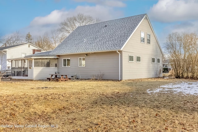 rear view of property featuring a yard, a shingled roof, and a sunroom