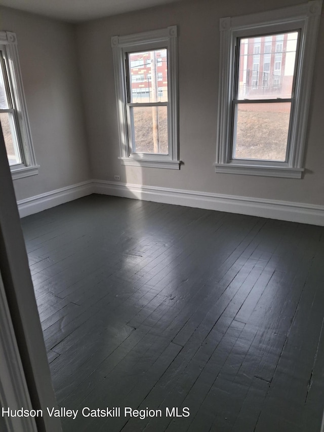 empty room featuring a wealth of natural light and dark hardwood / wood-style floors