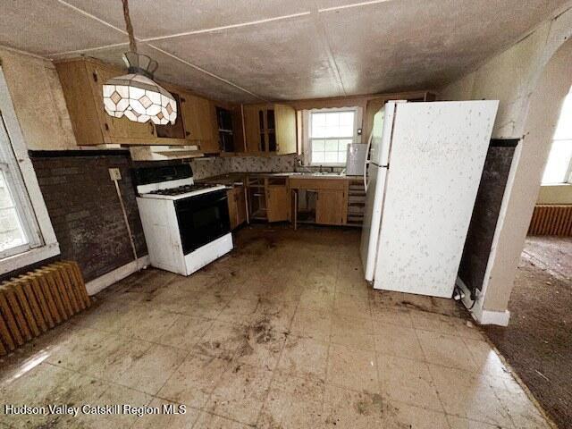 818 Cauterskill Rd, Catskill, NY 12414 - kitchen featuring gas range oven, freestanding refrigerator, radiator heating unit, and under cabinet range hood