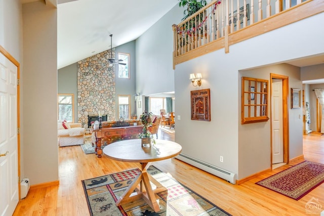 220 Botti Dr, Hunter, NY 12442 - dining room with a baseboard radiator, a ceiling fan, high vaulted ceiling, a stone fireplace, and wood finished floors