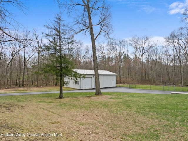 view of yard with an outbuilding, a forest view, a detached garage, and fence