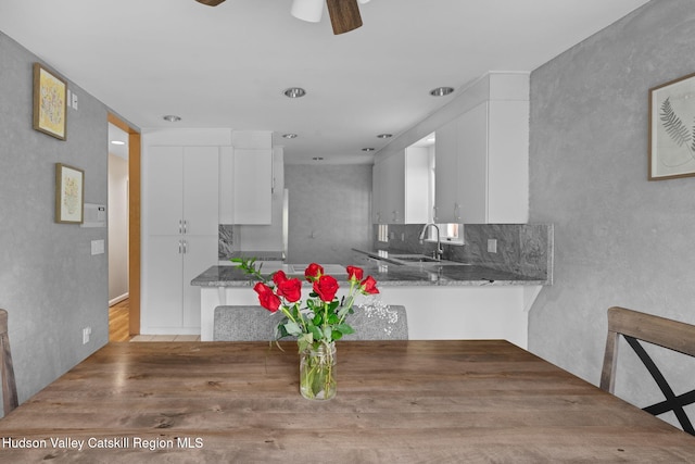 kitchen featuring stone counters, a ceiling fan, white cabinets, wood finished floors, and a sink