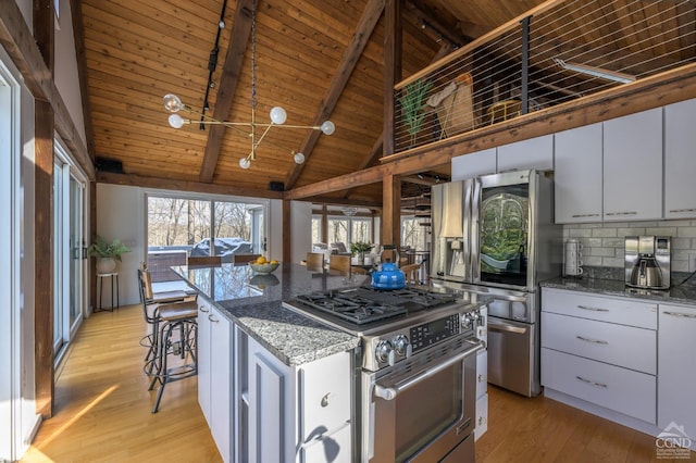 kitchen with appliances with stainless steel finishes, light wood finished floors, stone counters, high vaulted ceiling, and beam ceiling