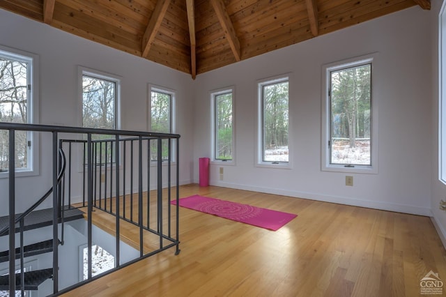 workout room with wood ceiling, wood finished floors, baseboards, and high vaulted ceiling