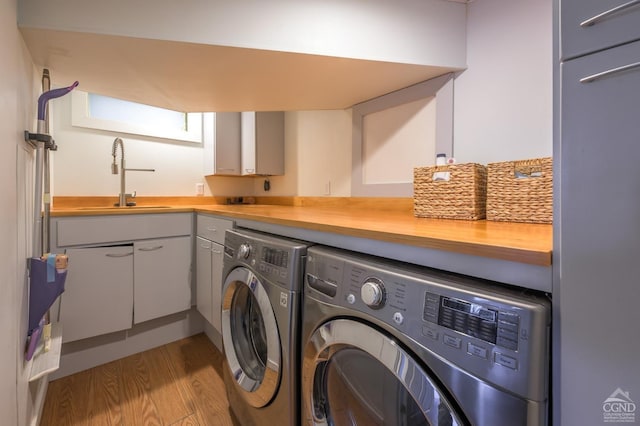 laundry room with washer and clothes dryer, wood finished floors, and cabinet space