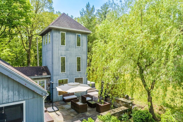 view of side of property with roof with shingles, a patio area, and outdoor lounge area
