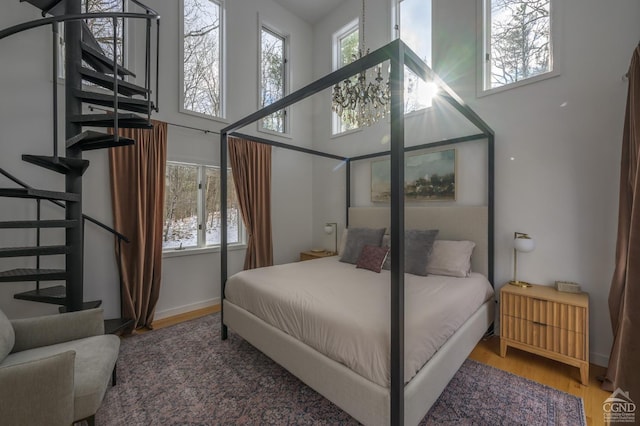 bedroom featuring wood finished floors, baseboards, and a towering ceiling
