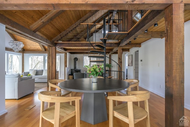 dining space with wood ceiling, a wood stove, light wood finished floors, baseboards, and stairs