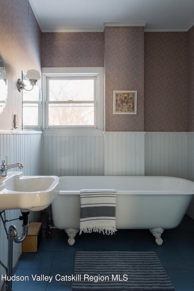 bathroom with a tub, ornamental molding, and tile patterned flooring