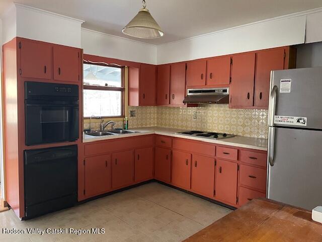 kitchen featuring pendant lighting, backsplash, black appliances, sink, and ornamental molding