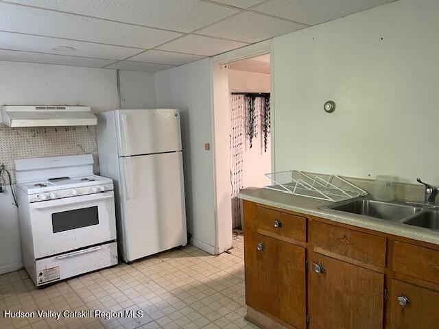 kitchen featuring ventilation hood, a drop ceiling, white appliances, and sink