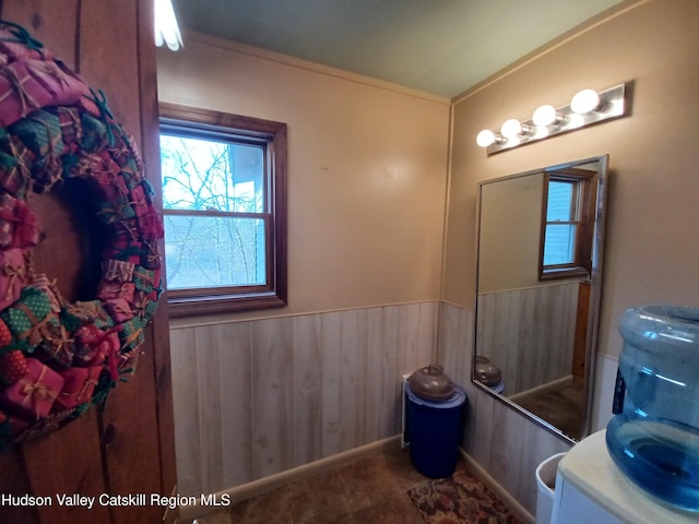 bathroom with tile patterned flooring, wooden walls, and crown molding