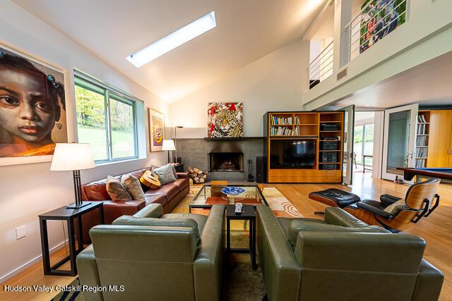 56 Winkelstern Ln, Kenoza Lake, NY 12750 - living area featuring wood finished floors, a fireplace, a skylight, and high vaulted ceiling