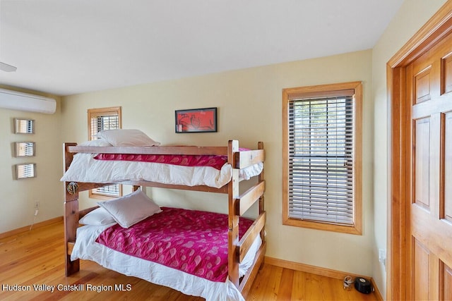 bedroom with a wall mounted air conditioner and hardwood / wood-style flooring