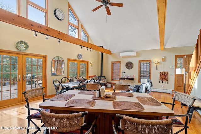 dining space with french doors, a wood stove, baseboard heating, a wall unit AC, and a high ceiling