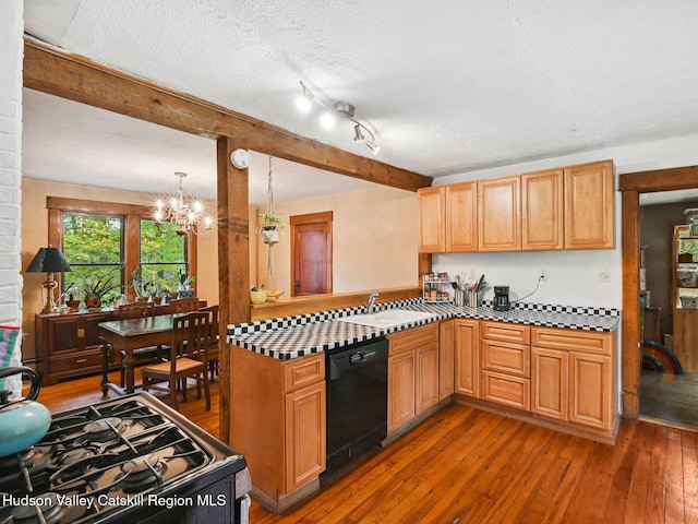 kitchen featuring dishwasher, sink, hanging light fixtures, dark hardwood / wood-style floors, and a textured ceiling