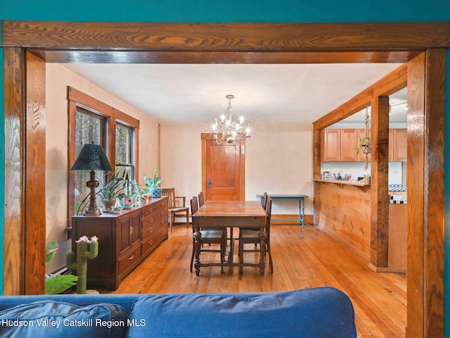 dining space with light wood-type flooring and a notable chandelier