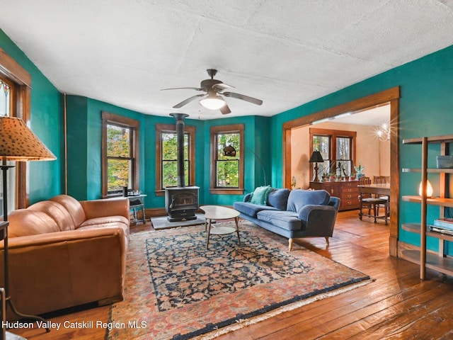 living room featuring hardwood / wood-style flooring, ceiling fan, and a wood stove