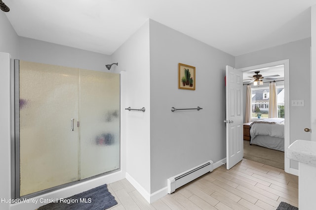ensuite bathroom with ensuite bathroom, baseboards, a ceiling fan, a shower stall, and a baseboard heating unit