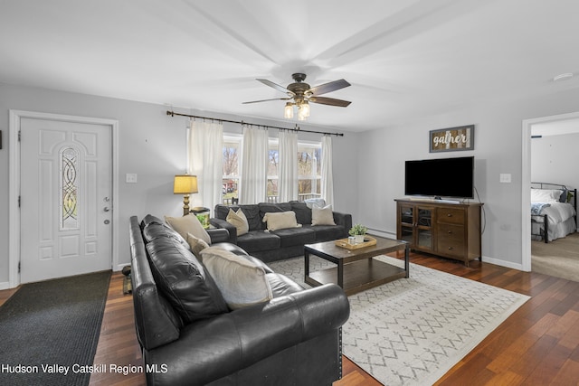 living room featuring dark wood-type flooring, baseboards, and ceiling fan