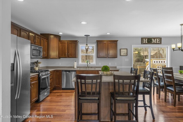 kitchen with a sink, appliances with stainless steel finishes, a breakfast bar area, and dark wood-type flooring