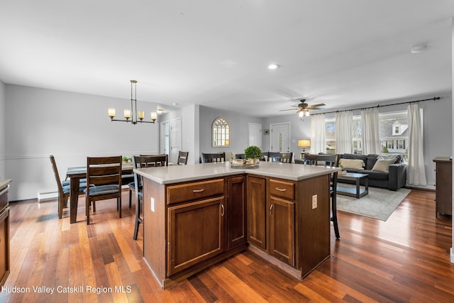 kitchen featuring dark wood-style flooring, light countertops, a breakfast bar area, and ceiling fan with notable chandelier
