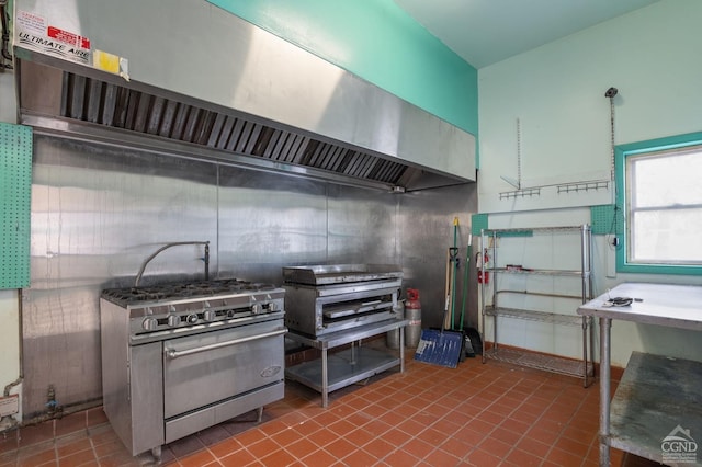 kitchen with stainless steel stove, wall chimney range hood, and tile patterned floors