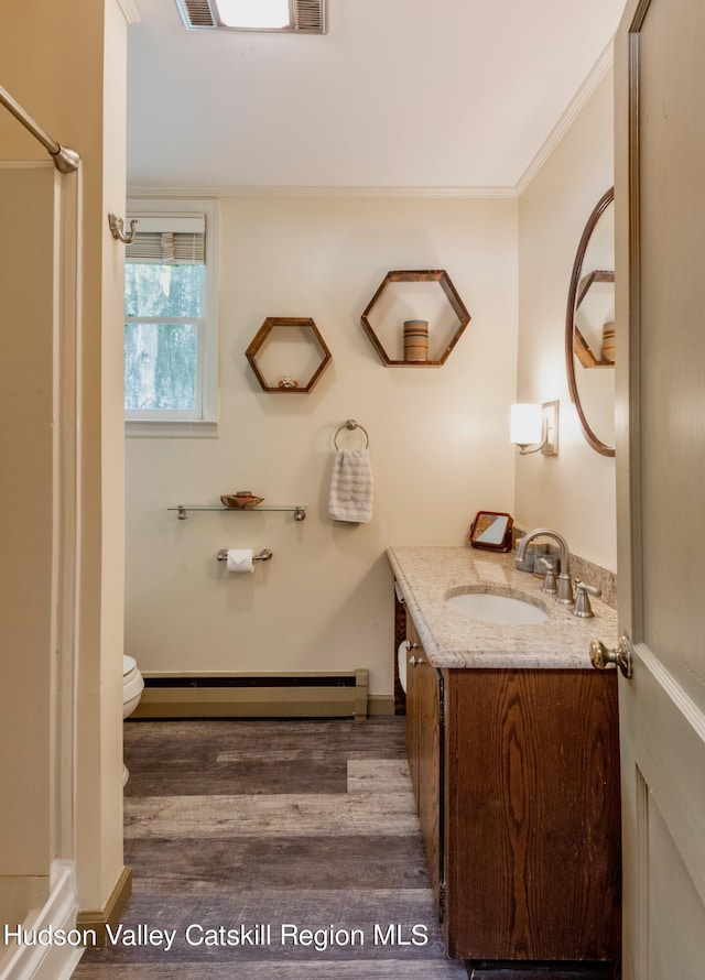 bathroom with baseboard heating, crown molding, toilet, vanity, and hardwood / wood-style flooring