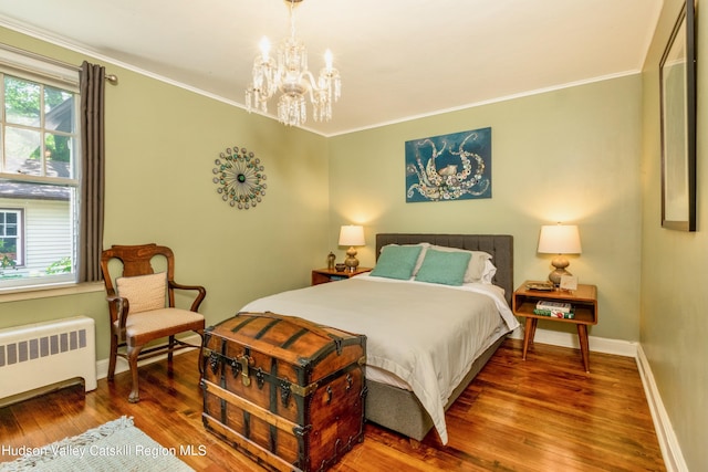 bedroom featuring a notable chandelier, wood-type flooring, ornamental molding, and radiator