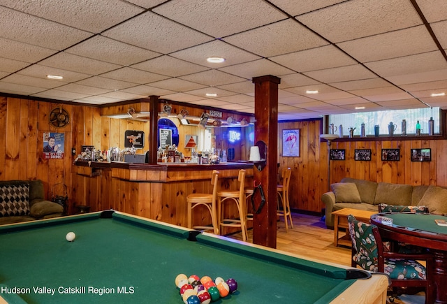 recreation room featuring billiards, wood-type flooring, wooden walls, and bar area