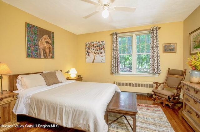 bedroom with hardwood / wood-style floors, ceiling fan, and radiator heating unit