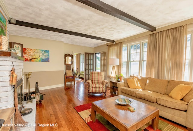 living room with a fireplace, beam ceiling, hardwood / wood-style flooring, and a wealth of natural light