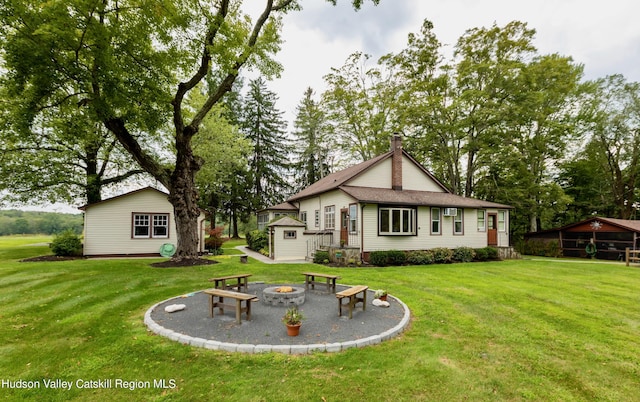 rear view of property with a yard and an outdoor fire pit