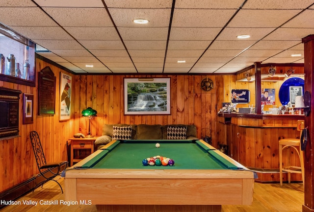 rec room with light wood-type flooring, a drop ceiling, wooden walls, and billiards