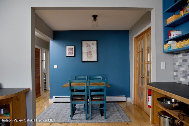 dining area with baseboards, french doors, wood finished floors, and a baseboard radiator