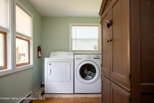laundry room featuring baseboard heating, baseboards, washing machine and clothes dryer, and plenty of natural light