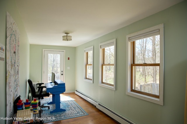 office space featuring plenty of natural light, baseboard heating, and wood finished floors